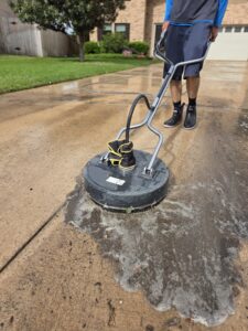 Pressure washing driveway in Austin TX using a surface cleaner to remove dirt and buildup